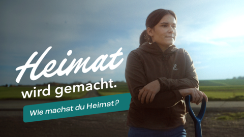 Heimatmacherin Helena Wolf im Vordergrund auf Spaten gestützt und schaut in die Ferne. Im Hintergrund Kartoffelacker mit Licht am Abend. Dazu der Slogan "Heimat wird gemacht. Wie machst du Heimat?"